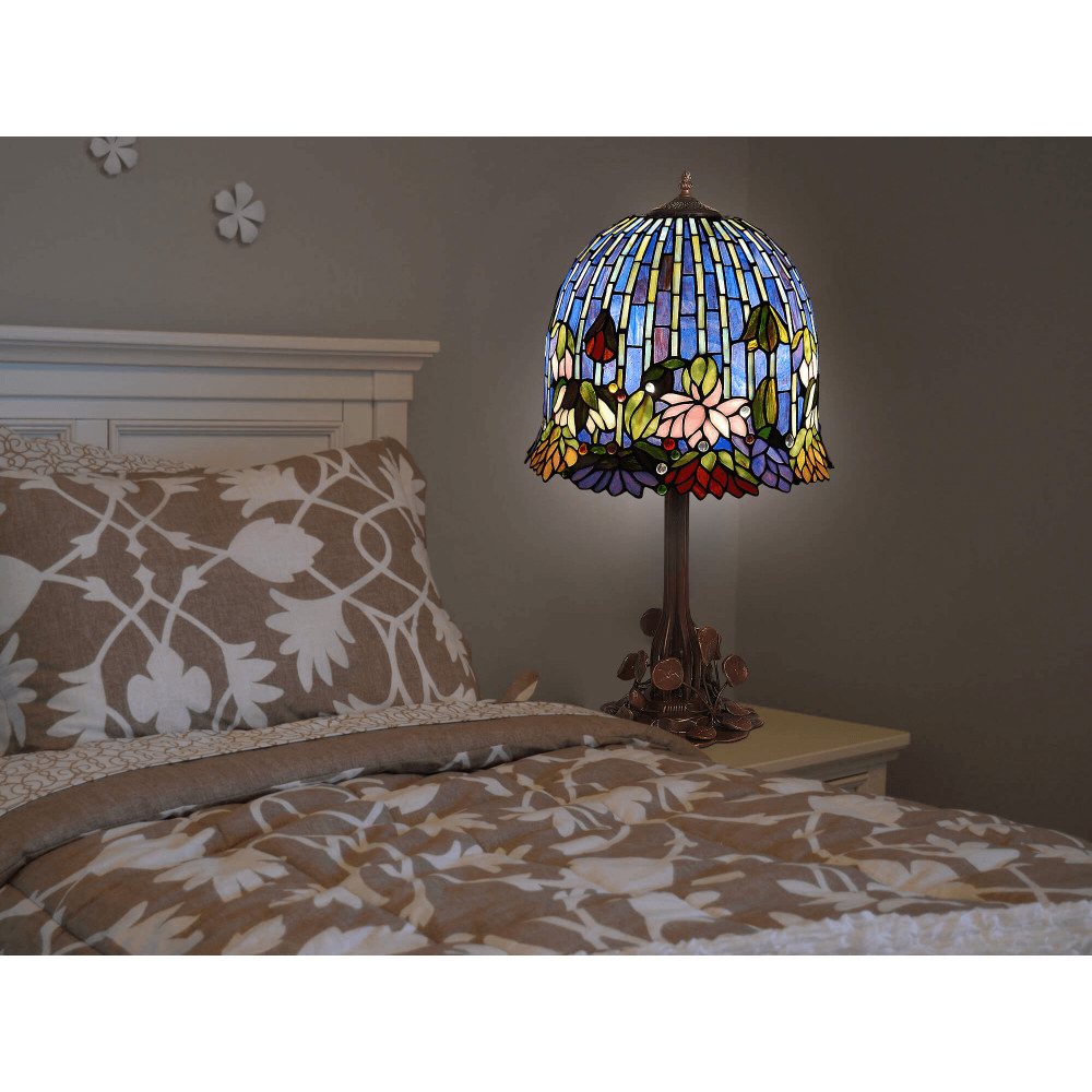 Tiffany Tischlampe Lotus – Eleganz und Kunst für Ihr Zuhause, in einem Schlafzimmer platziert. Die Lampe strahlt stimmungsvolles Licht und fügt sich harmonisch in die Einrichtung ein.