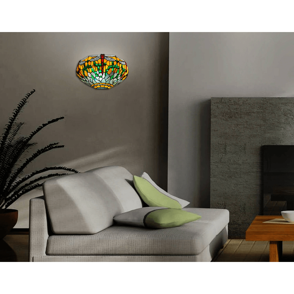 Designer Tiffany Wandleuchte mit rotem und grünem Libellenmotiv, installiert in einem modernen Wohnzimmer über einem hellen Sofa.