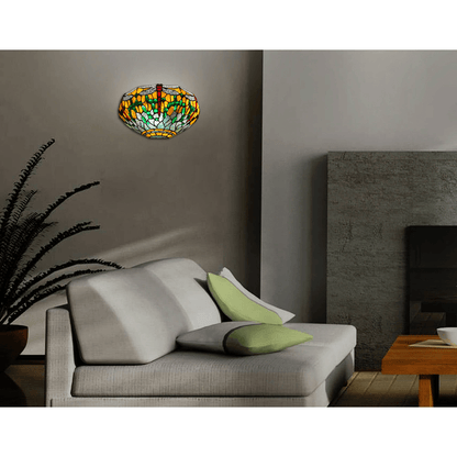 Designer Tiffany Wandleuchte mit rotem und grünem Libellenmotiv, installiert in einem modernen Wohnzimmer über einem hellen Sofa.