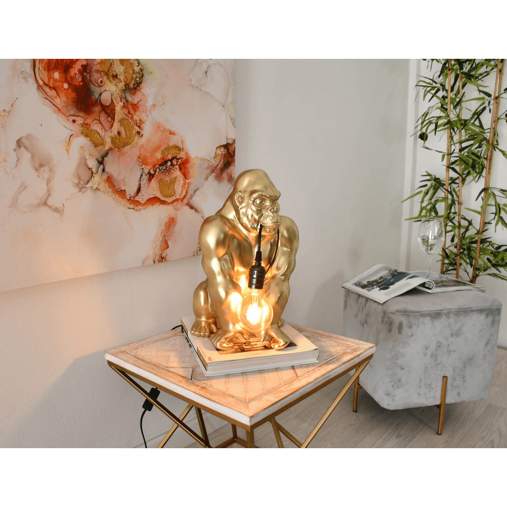 Designer Tischlampe Orang-Utan aus Harz mit Goldeffekt – Installierte Tischlampe auf einem eleganten Tisch, umgeben von stilvollem Wohnambiente.