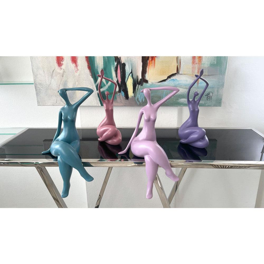 Erwachende Frau: Moderne violette Skulptur aus satiniertem Harz, präsentiert neben weiteren künstlerischen Figuren, zeigt die Vielfalt und Eleganz zeitgenössischer Kunst in einem stilvollen Ambiente.