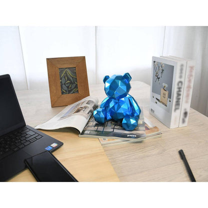 Facettierte blaue Bärchen-Skulptur aus Kunstharz - Modernes Metalleffekt-Design, stilvoll platziert auf einem Schreibtisch mit Zeitschriften und einem Laptop, perfekt für moderne Büros.
