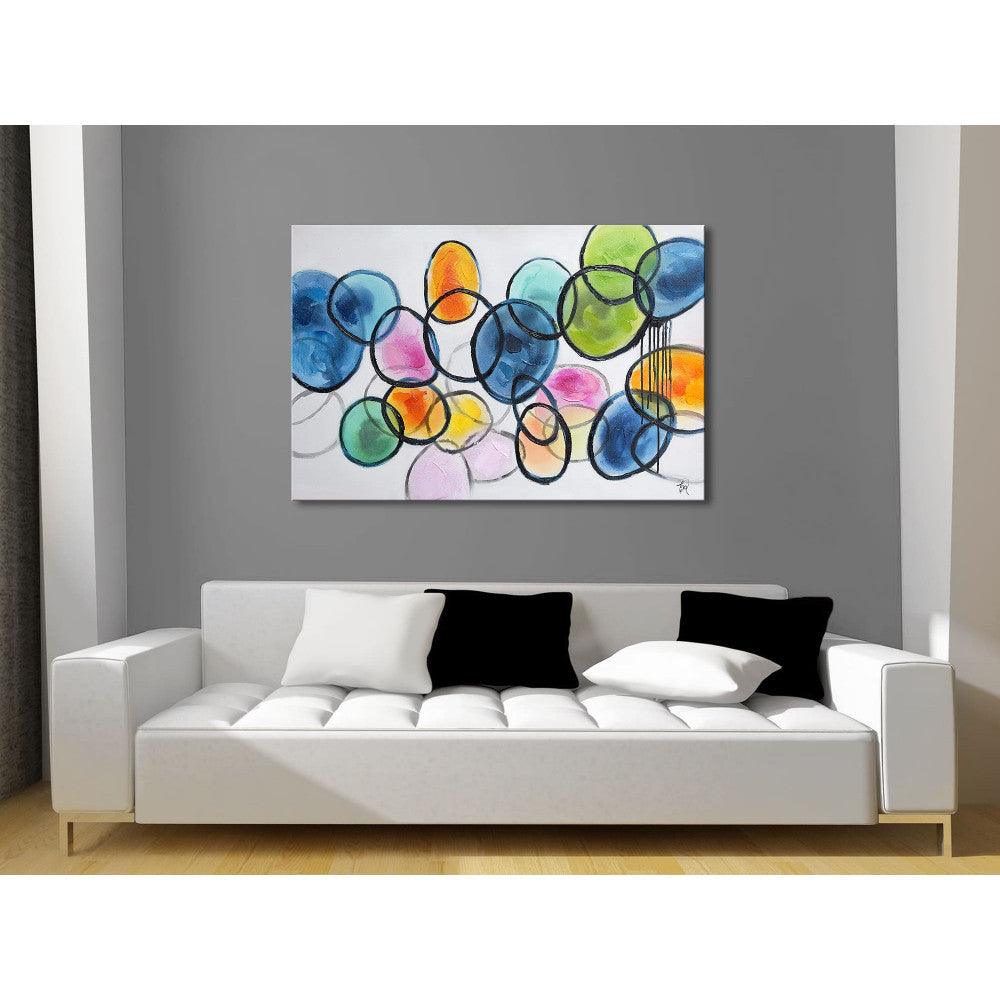 Farbige Kreise: Handgemaltes Abstraktes Wandgemälde von Edgar Ramirez, präsentiert über einem eleganten Sofa in einem modern gestalteten Wohnzimmer.