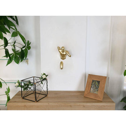 Goldener Läufer – Moderne Wandskulptur aus Metalleffekt-Harz, präsentiert an einer Wand neben Pflanzen und einem Bilderrahmen, stilvolle Interior-Dekoration.