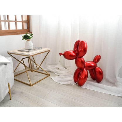 Exquisite Rubinrote Balloon-Hund Skulptur aus Kunstharz in einem modernen Wohnraum, platziert neben einem goldenen Tisch. Die Skulptur zeigt glänzende rubinrote Ballonformen, die einen verspielten und kreativen Akzent setzen.