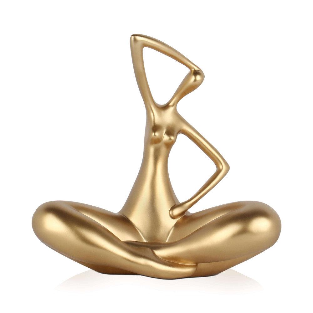 Kleine Evolution – Moderne Kunstharzskulptur mit Goldmetalleffekt, präsentiert eine stilisierte Frau in entspannter Sitzposition mit eleganten Linien.