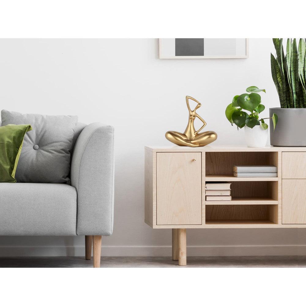 Kleine Evolution – Moderne Kunstharzskulptur mit Goldmetalleffekt, platziert in einem modernen Wohnraum auf einem Sideboard mit Pflanzen im Hintergrund.