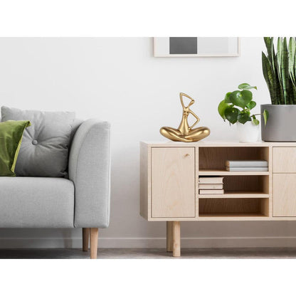 Kleine Evolution – Moderne Kunstharzskulptur mit Goldmetalleffekt, platziert in einem modernen Wohnraum auf einem Sideboard mit Pflanzen im Hintergrund.