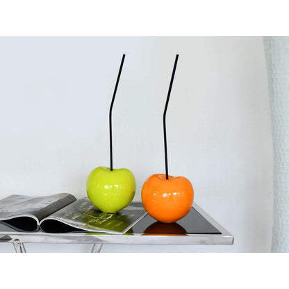 Charmante Pop Art Skulptur: Kleine Gelbe Kirsche aus lackiertem Harz, neben einer leuchtend grünen und orangefarbenen Apfel-Skulptur auf einem Tisch.