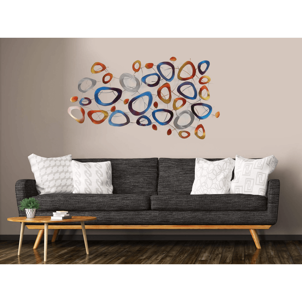 Farbige Ring-Komposition: Handgefertigte Metall-Wandskulptur für moderne Wohnräume, präsentiert an einer Wand über einem stilvollen Sofa, das ihr elegantes Design unterstreicht.