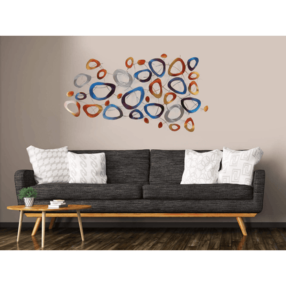 Farbige Ring-Komposition: Handgefertigte Metall-Wandskulptur für moderne Wohnräume, präsentiert an einer Wand über einem stilvollen Sofa, das ihr elegantes Design unterstreicht.