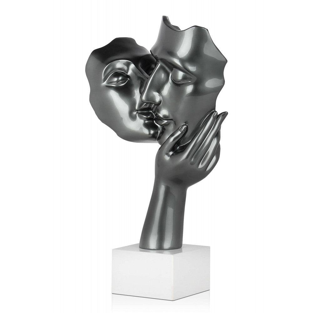 Kuss der Zärtlichkeit: Detailansicht einer modernen Skulptur aus Kunstharz mit Metalleffekt, die den innigen Kuss zweier Gesichter darstellt, auf einem stilvollen Marmorsockel.