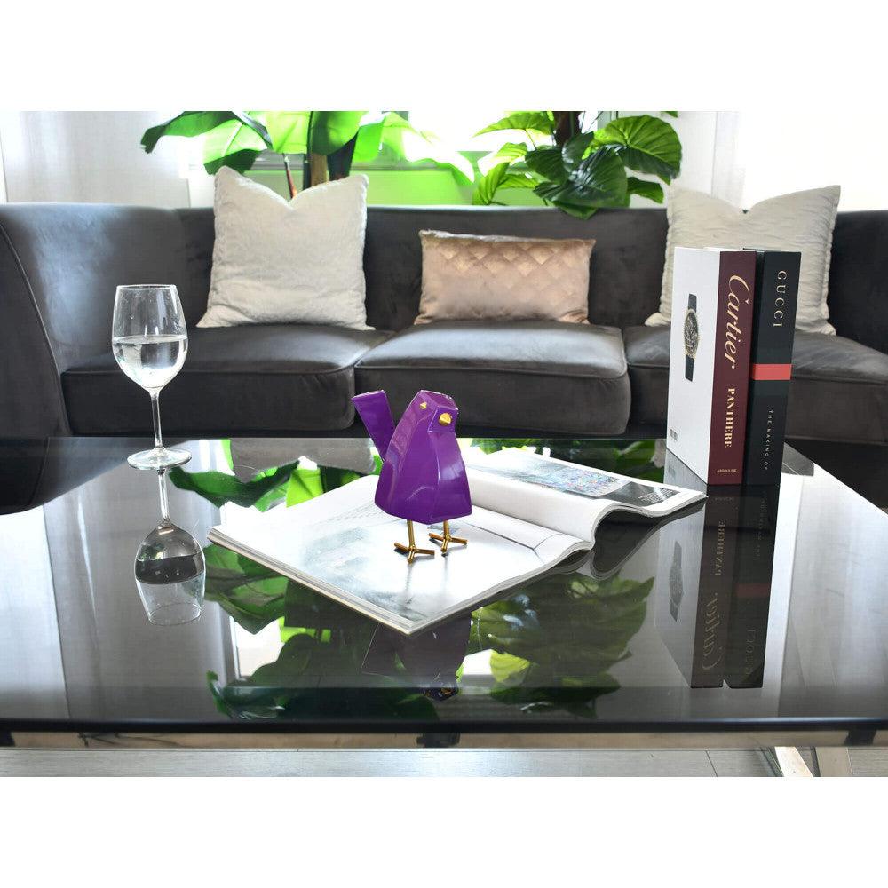 Moderne geometrische Lilaskulptur aus lackiertem Harz mit Metalleinsätzen, lilafarbener Vogel auf einem Tisch, dekoratives Element in einem modernen Wohnzimmer.