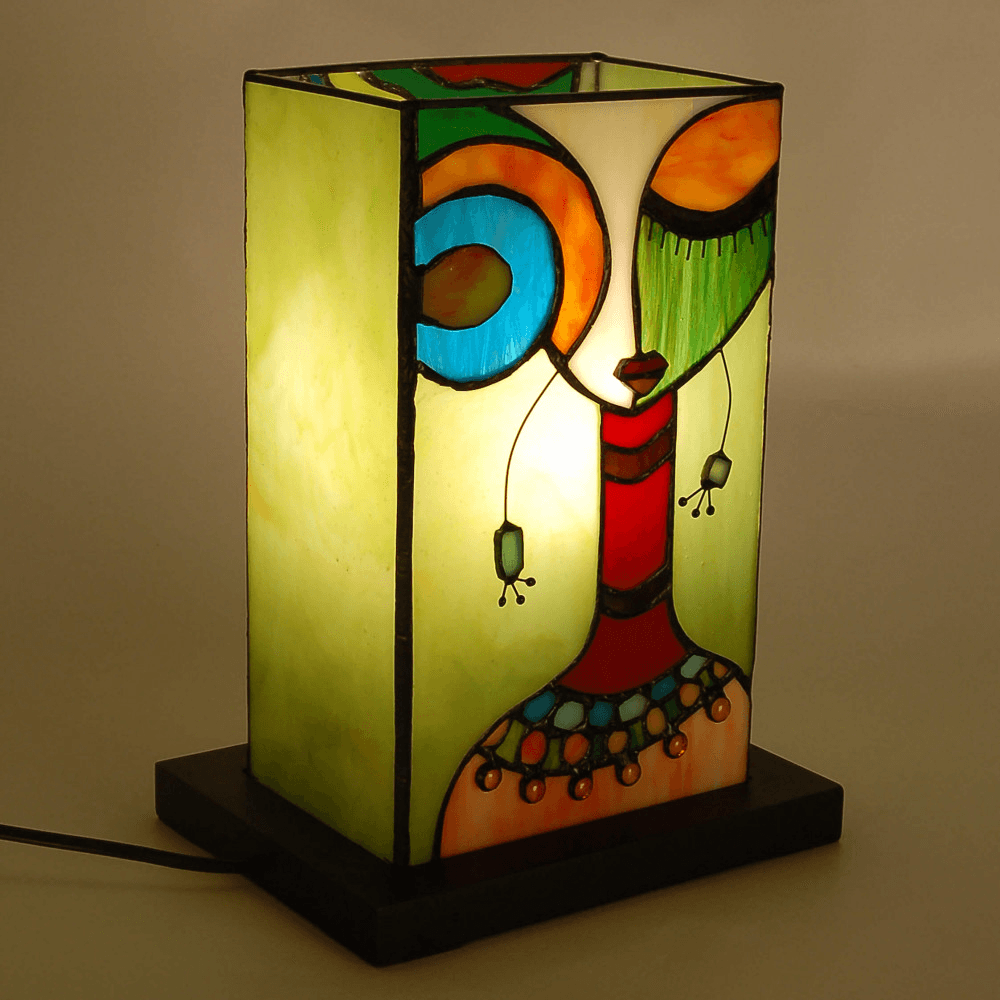 Ethnische Nachttischlampe mit Frauengesicht aus Tiffany-Glas leuchtend dargestellt, ideal für kreative Beleuchtung im Wohnraum.