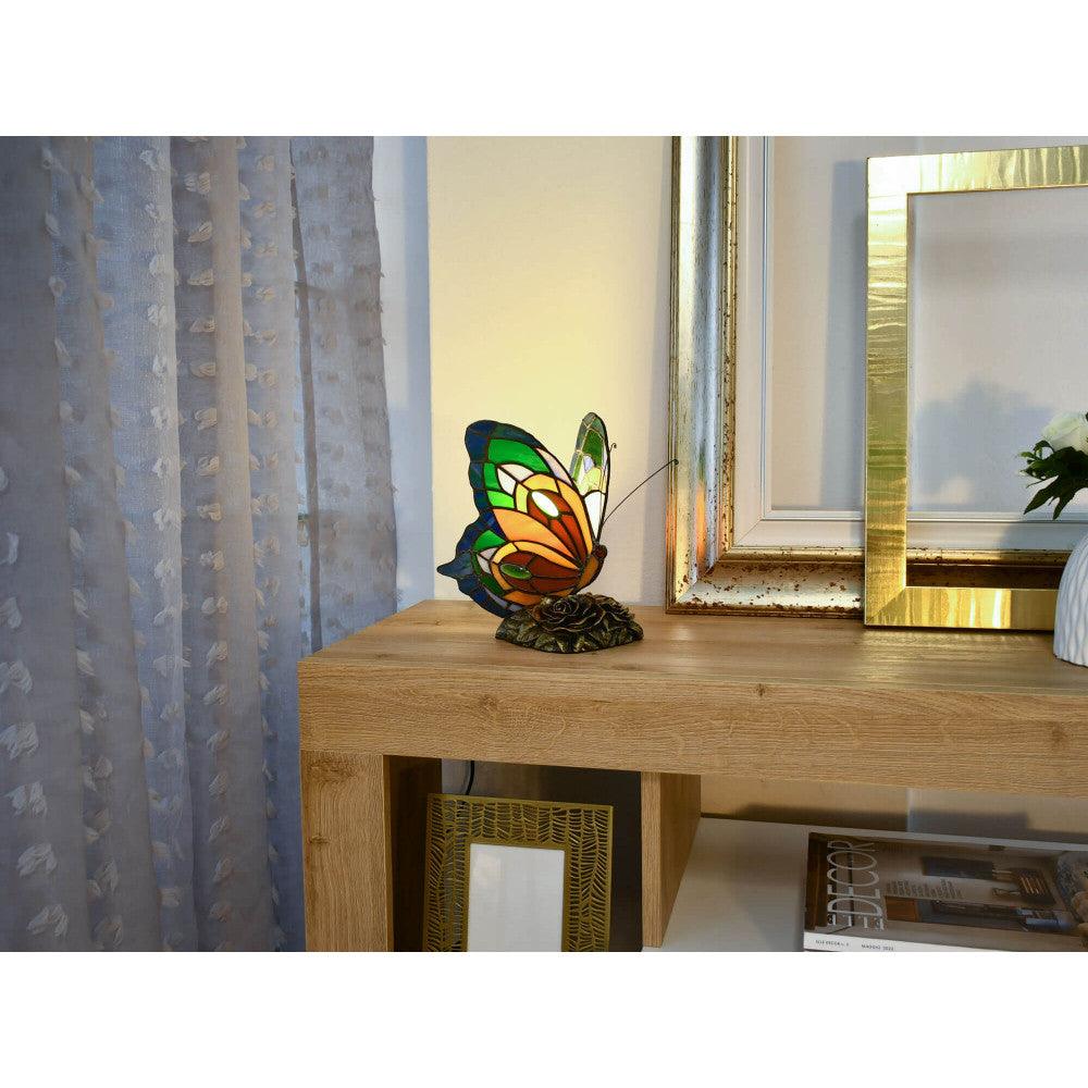 Die Tiffany Nachttischlampe im Schmetterlingsdesign in lebhaften Farben steht dekorativ auf einem modernen Regal in einem gemütlichen Wohnraum.
