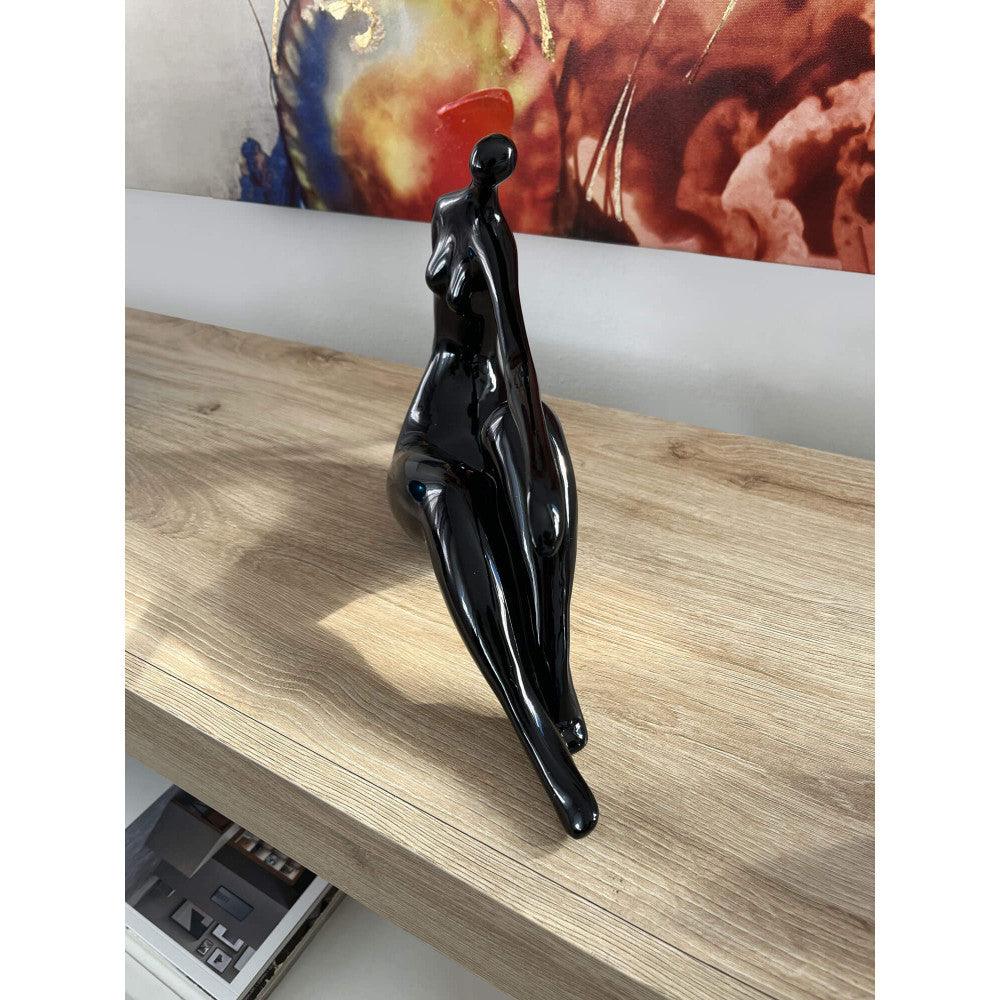 Ruhende Dame – elegante figurative Skulptur in Schwarz aus lackiertem Kunstharz, detailreich und modern, umgeben von einem klaren und minimalistischen Raumdesign.