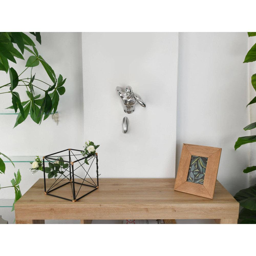 Elegante Figurative Skulptur Silberner Läufer mit Spiegeleffekt aus Kunstharz, platziert auf einem minimalistischen Regal in einem modernen Wohnraum mit Pflanzen und einem Bilderrahmen.