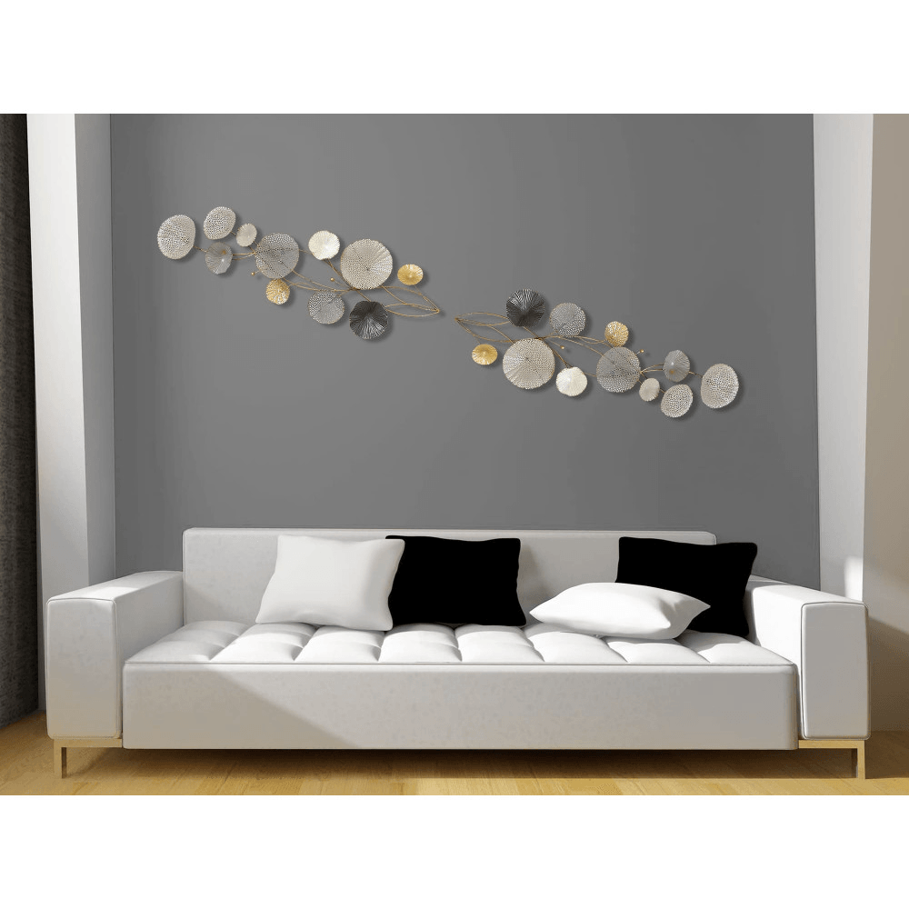 Stilisierte Wanddekoration aus Metall: Elegante Seerosen in Grau und Gold, präsentiert über einem modernen Sofa in einem stilvollen Raum.