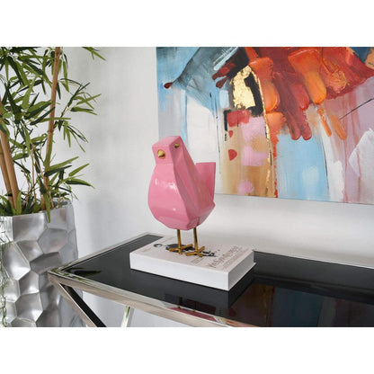 Die moderne geometrische Skulptur 'Vöglein rosa' aus lackiertem Harz, stilvoll auf einem Tisch platziert, umgeben von farbenfroher Kunst, perfektes Dekorationselement für zeitgemäße Innenräume.
